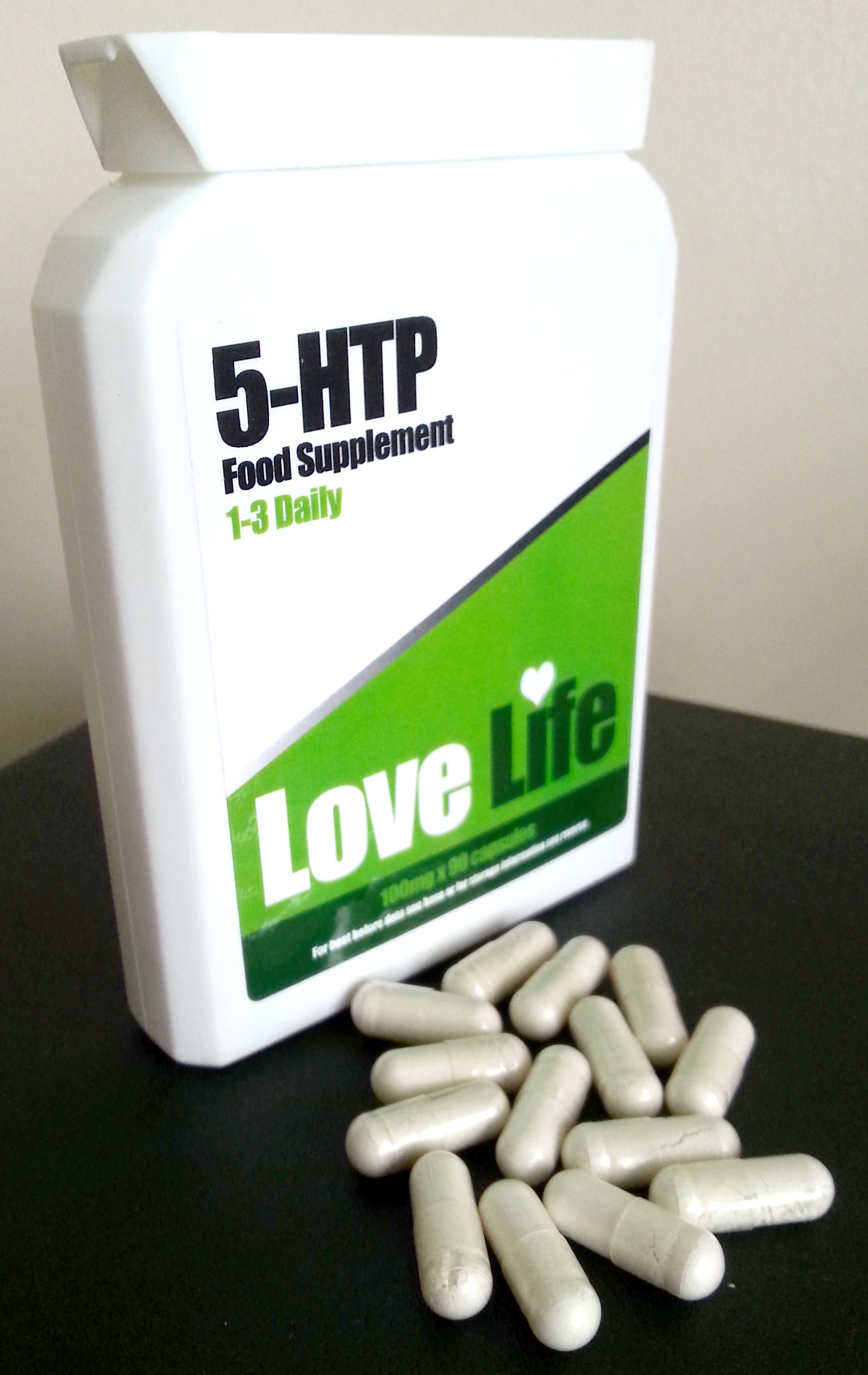 5-HTP food supplement bottle with capsules on a black surface