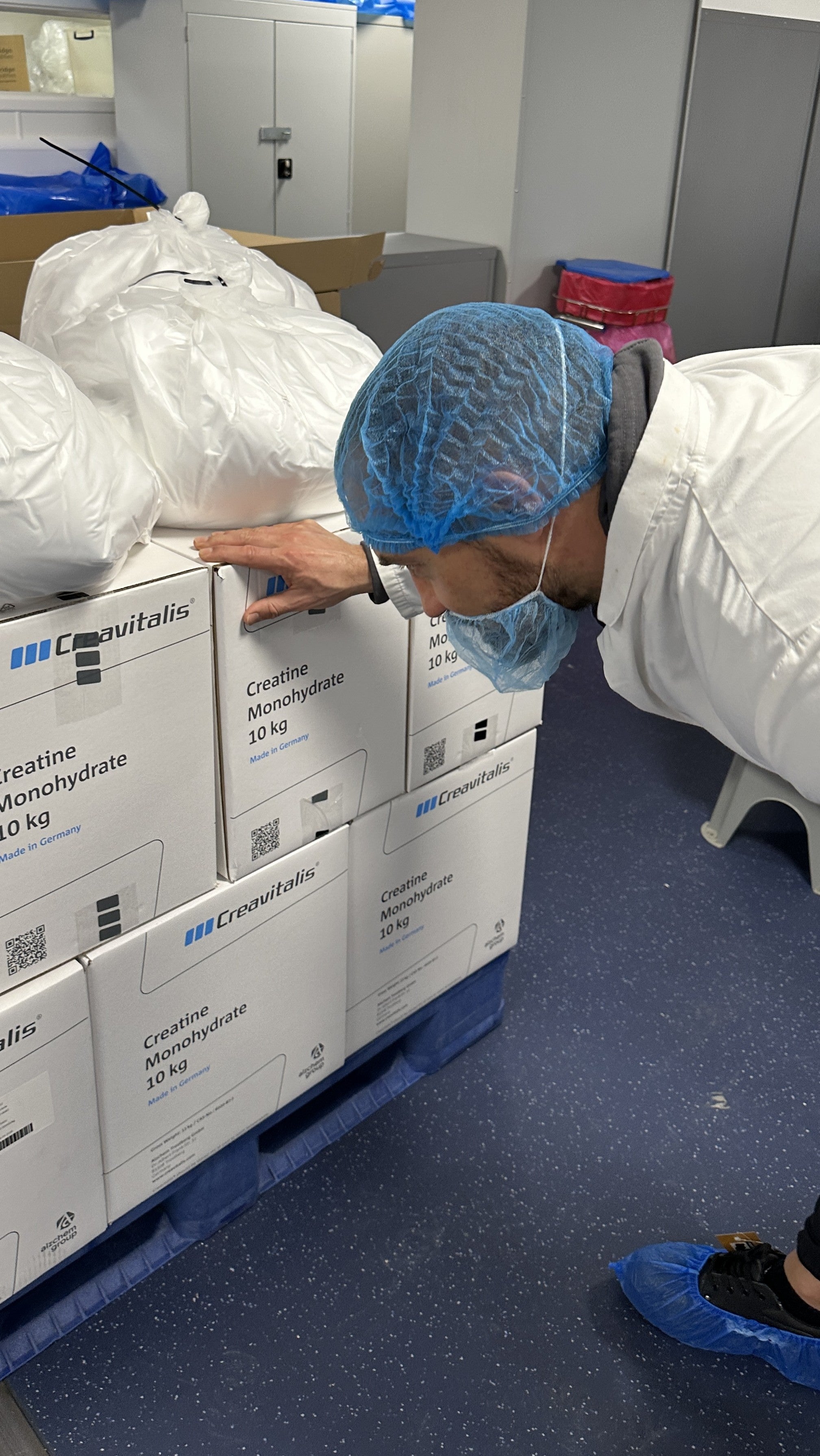 Person wearing a blue hairnet inspecting boxes labeled 'Crescent' on a pallet.