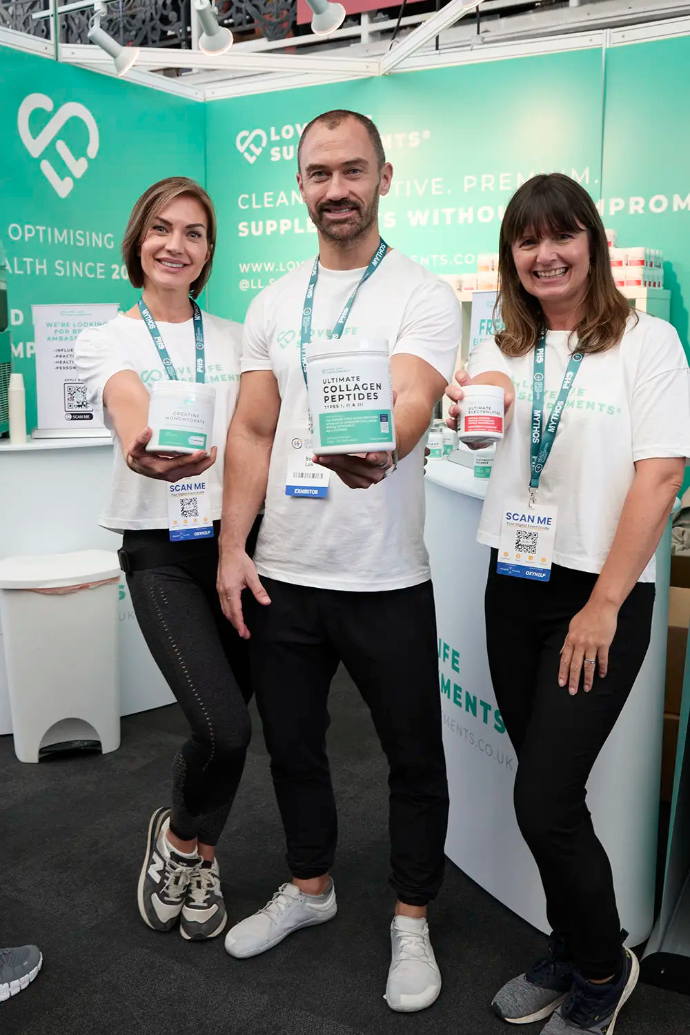 love life supplements team Three people holding products in front of a promotional backdrop